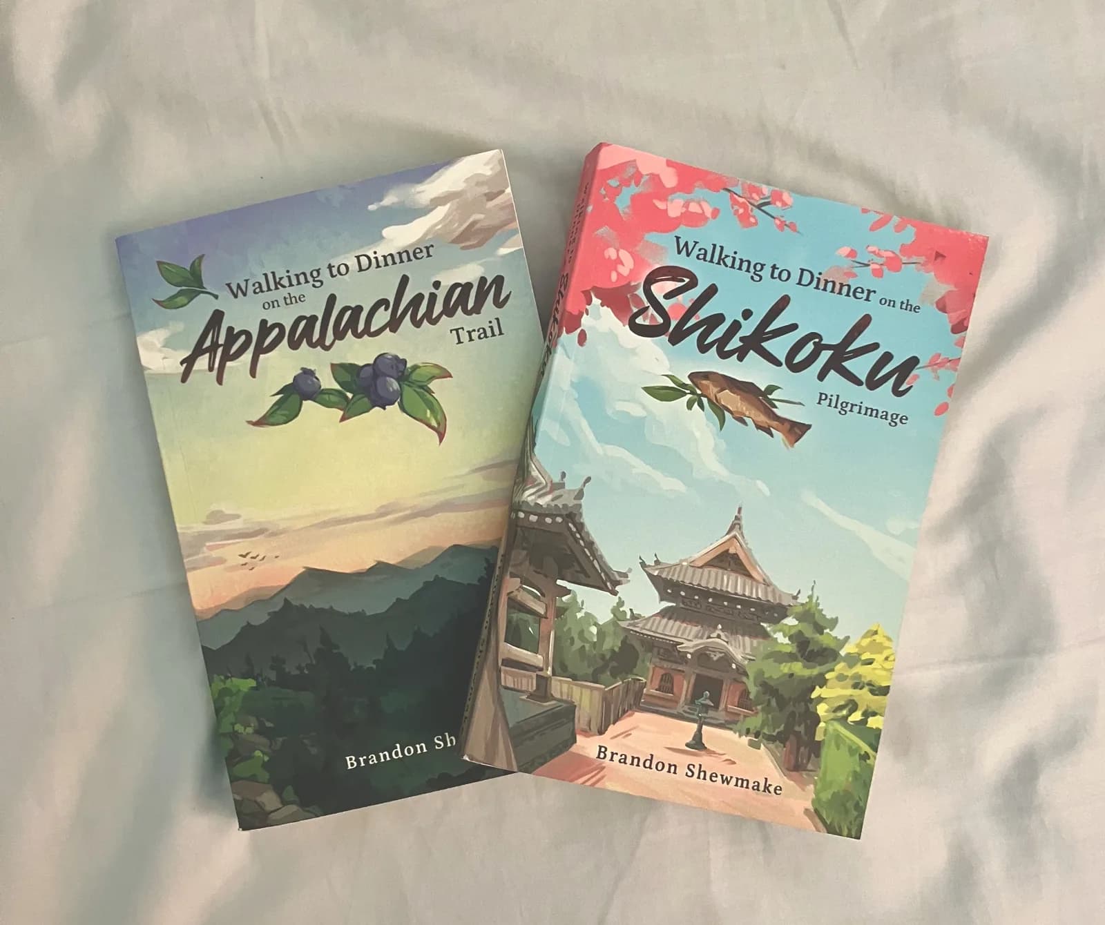 Printed Copies Photo of printed paperback copies of 'Walking to Dinner on the Appalachian Trail' and 'Walking to Dinner on the Shikoku Pilgrimage' by Brandon Shewmake, lying side by side